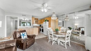 A modern kitchen with a central island, a dining area with white chairs, and a brown leather sofa with a starfish pillow. - Oceanfront, 2nd Floor, Sea View, 2 Pools (Panama City Beach)
