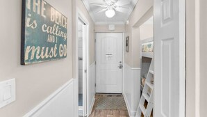 A hallway with a ceiling fan, a door, and a wall-mounted sign.