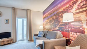 A modern hotel room with a sofa, armchair, and a large window. - Vibrant Central Studio (Lisbon)