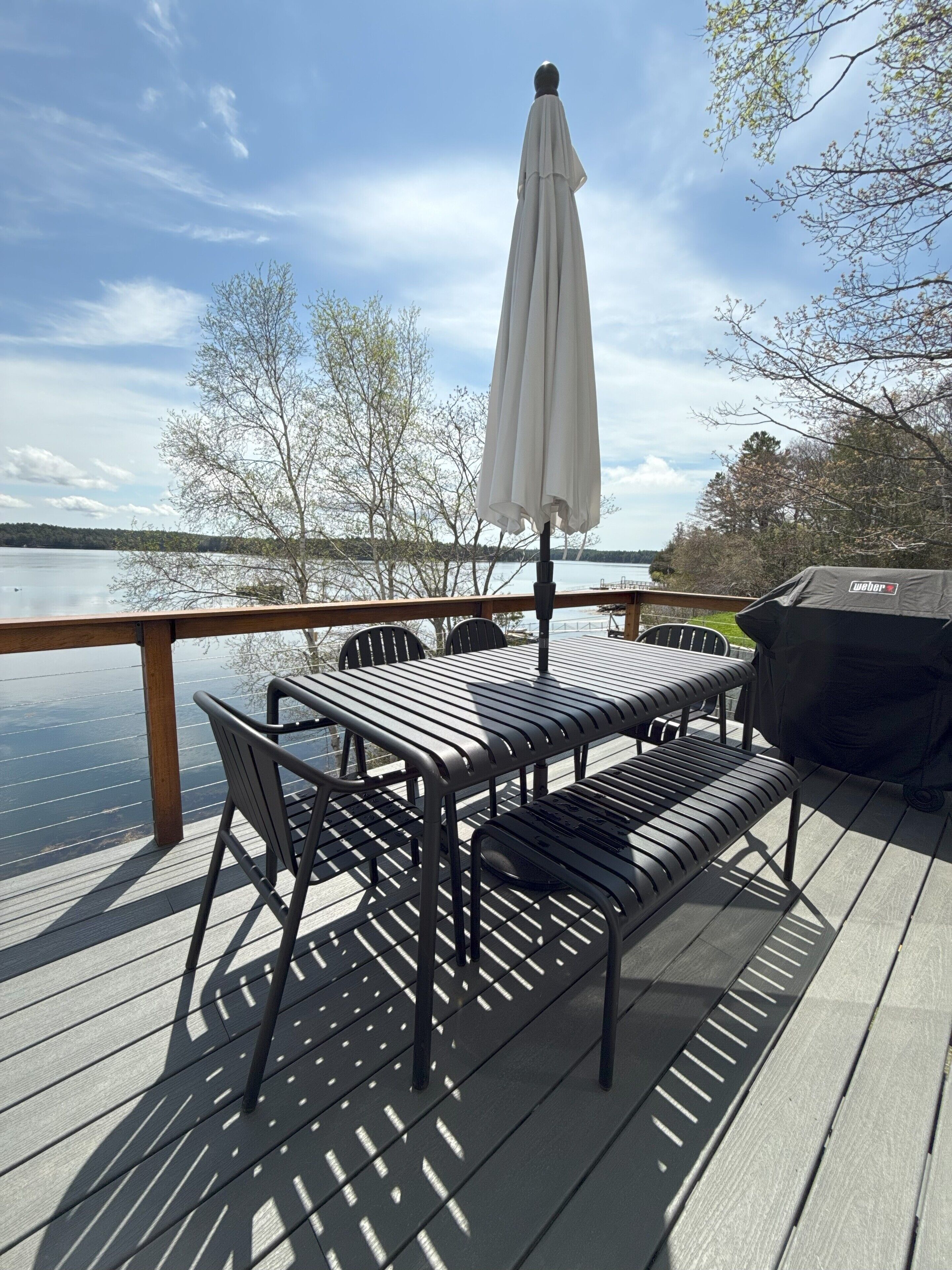 A deck with a table and chairs, overlooking a body of water.