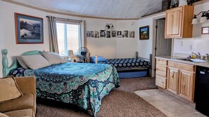 A cozy bedroom with two beds, a wooden cabinet, and a window with curtains. - Granary/Silo 2nd Floor Studio in Dinosaurland with AC, WiFi (Vernal)