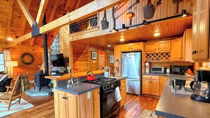 A wooden cabin interior with a kitchen featuring a stove, refrigerator, and wooden cabinets. - 9N Mountainside Cabin in Franconia Heights, Dog Friendly, Stunning Views! (Franconia)