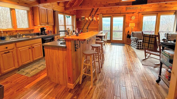 A wooden cabin interior with a kitchen, bar area, and seating. - 9N Mountainside Cabin in Franconia Heights, Dog Friendly, Stunning Views! (Franconia)