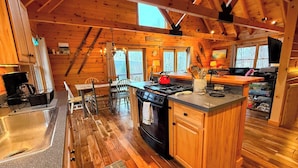A cabin interior with a kitchen, dining area, and a large window. - 9N Mountainside Cabin in Franconia Heights, Dog Friendly, Stunning Views! (Franconia)