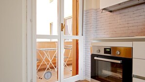 A kitchen with a white oven, a digital clock, and a brick wall. - Our newly renovated property is designed to offer you maximum comfort. The bright and spacious bedroom is equipped with a comfortable double bed, ideal for a regenerating sleep. The living room is perfect for relaxing, with a sofa that turns into a bed t (Pisa)
