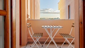 A balcony with two wooden chairs and a small table, overlooking a cityscape. - Our newly renovated property is designed to offer you maximum comfort. The bright and spacious bedroom is equipped with a comfortable double bed, ideal for a regenerating sleep. The living room is perfect for relaxing, with a sofa that turns into a bed t (Pisa)