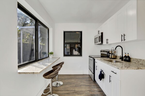 A modern kitchen with white cabinets, a granite countertop, and a large window. - La Bella vacations 5 (Fort Lauderdale)