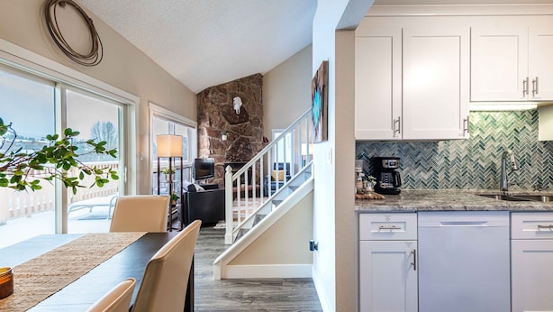 A modern kitchen with white cabinets, a herringbone tile backsplash, and a dining area with a table and chairs. - 4BR Mountain Retreat , Fireplace, Deck with Views, RMNP (Fraser)