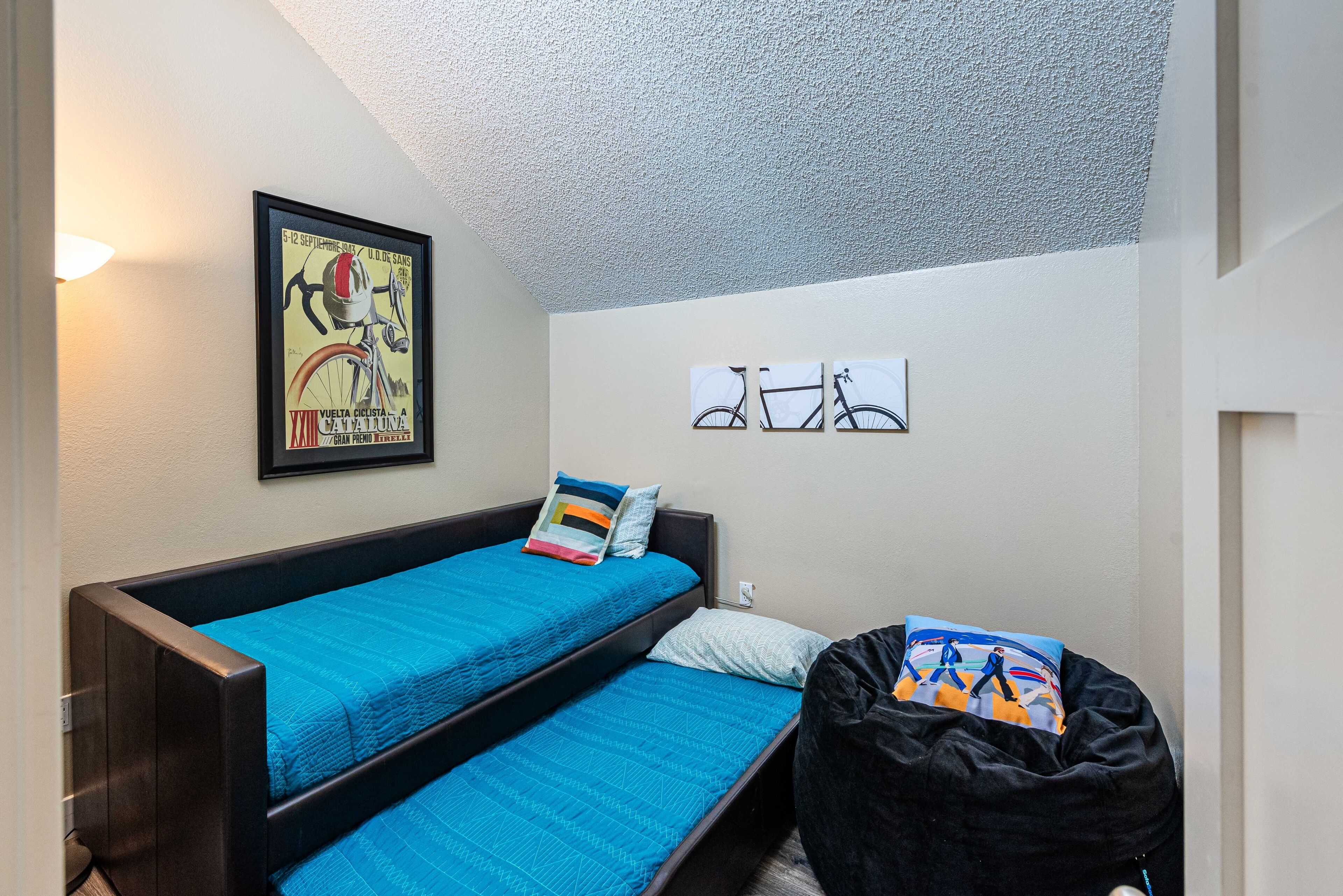 A room with a bunk bed, a framed poster on the wall, and a small window.