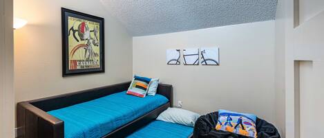 A room with a bunk bed, a framed poster on the wall, and a small window.