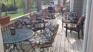 A wooden deck with outdoor furniture, including a round table and two sofas with floral upholstery. - Charming 1-bedroom apartment in cool Garner, minutes from Raleigh (Garner)