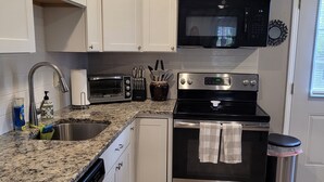 A modern kitchen with white cabinets, a stainless steel oven, a microwave, and a dishwasher. - Charming 1-bedroom apartment in cool Garner, minutes from Raleigh (Garner)