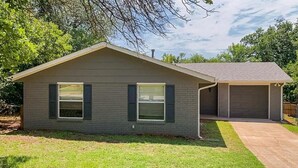A single-story house with a garage, a front lawn, and a tree in the background. - Lazy E Country Cozy in Edmond Oklahoma (Edmond)