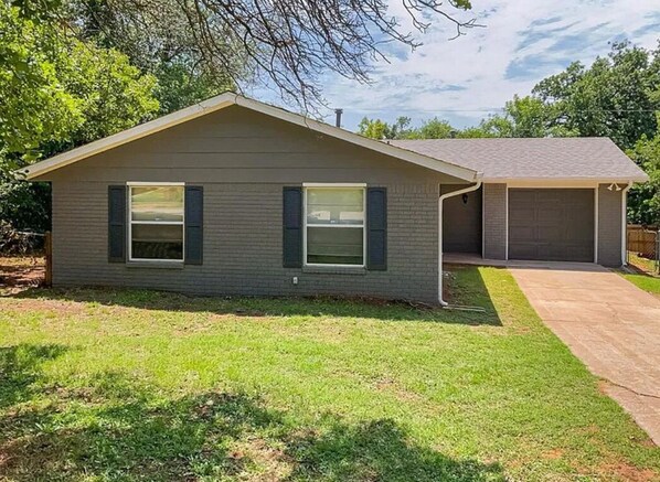 A single-story house with a garage, a front lawn, and a tree in the background. - Lazy E Country Cozy in Edmond Oklahoma (Edmond)