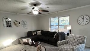 A living room with a sectional sofa, a patterned armchair, a coffee table, and a ceiling fan. - Lazy E Country Cozy in Edmond Oklahoma (Edmond)