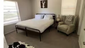 A bedroom with a bed, a ceiling fan, a chair, and a window. - Lazy E Country Cozy in Edmond Oklahoma (Edmond)