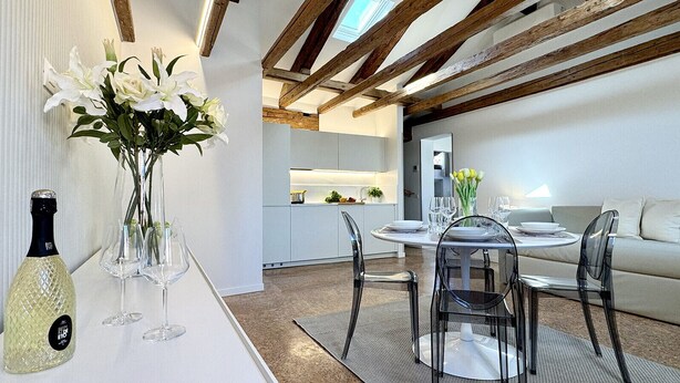A modern dining area with a white table, clear chairs, and a vase of white flowers. - Residence Salieri (500mt. from St. Mark's Square) (Venecia)