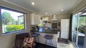 Une cuisine moderne dotée d’un îlot central, de tabourets de bar et offrant une vue sur l’extérieur.