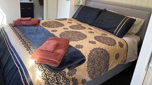 Un lit bien fait, avec une literie à motifs et deux serviettes pliées.
