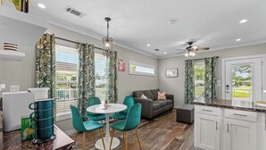 A modern kitchen with a dining area, a sofa, and a view of the outdoors.