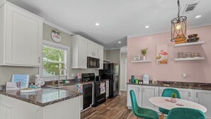 A modern kitchen with white cabinets, a black refrigerator, and a teal dining area.