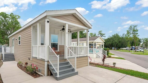 A single-story house with a porch, a small staircase, and a covered outdoor area.