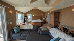 Amplia sala de estar con un sofá grande, una cama de madera y una mesa de comedor.