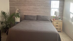 A bedroom with a bed, a nightstand, a lamp, a potted plant, and a ceiling fan. - Charming 3-bedroom house with AC, WiFi in fantastic Coachella (Coachella)