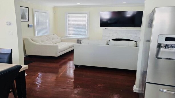 A compact living space with a kitchenette, a sofa, and a flat-screen TV mounted above the fireplace.