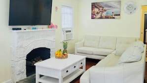 A living room with a flat-screen TV, a fireplace, a white sofa, and a coffee table.