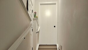 Una escalera de madera con barandillas blancas que lleva a una puerta cerrada.