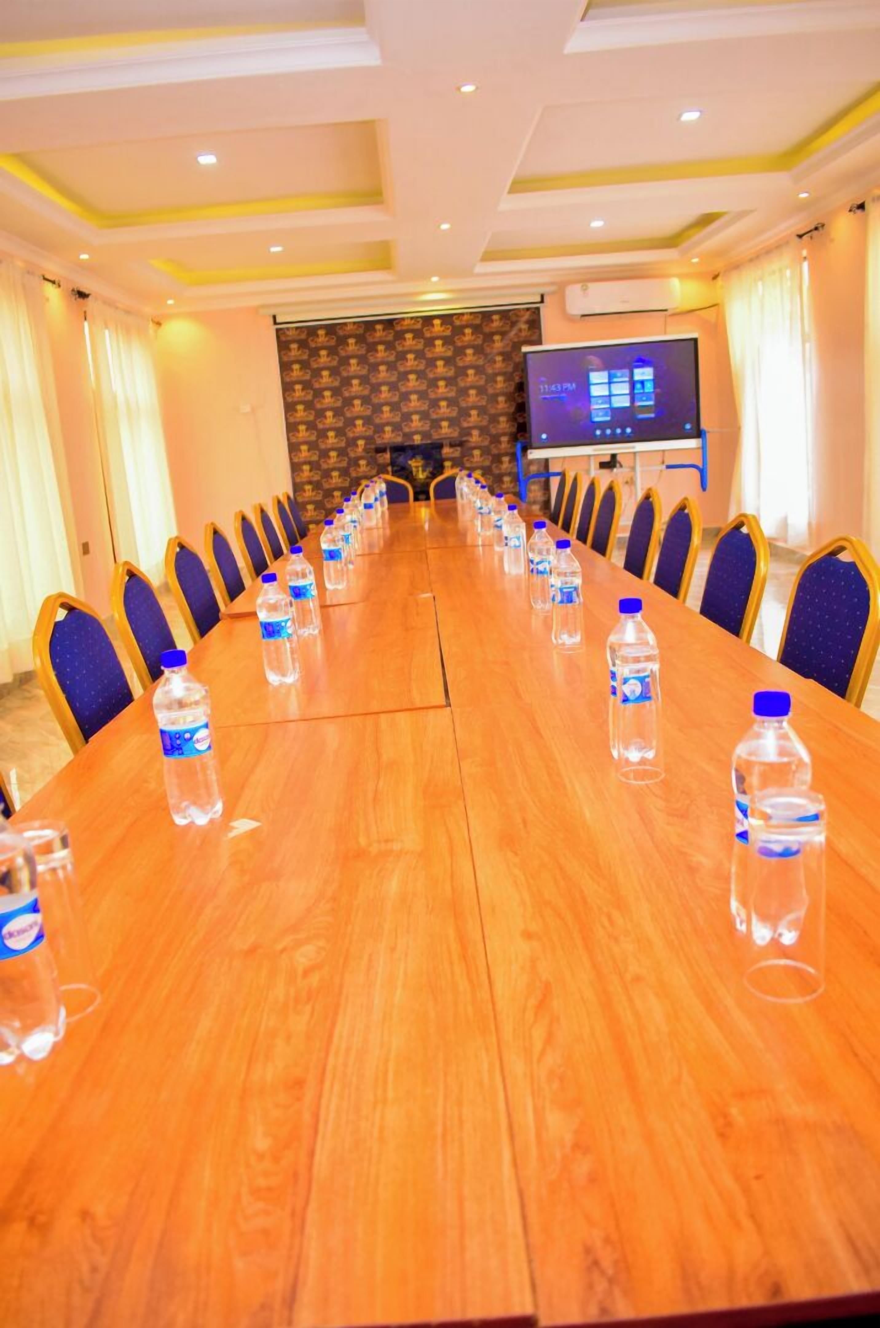 A conference room with a long wooden table, rows of chairs, and water bottles.