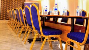 Una sala conferenze con un lungo tavolo, sedie blu e bottiglie d'acqua.