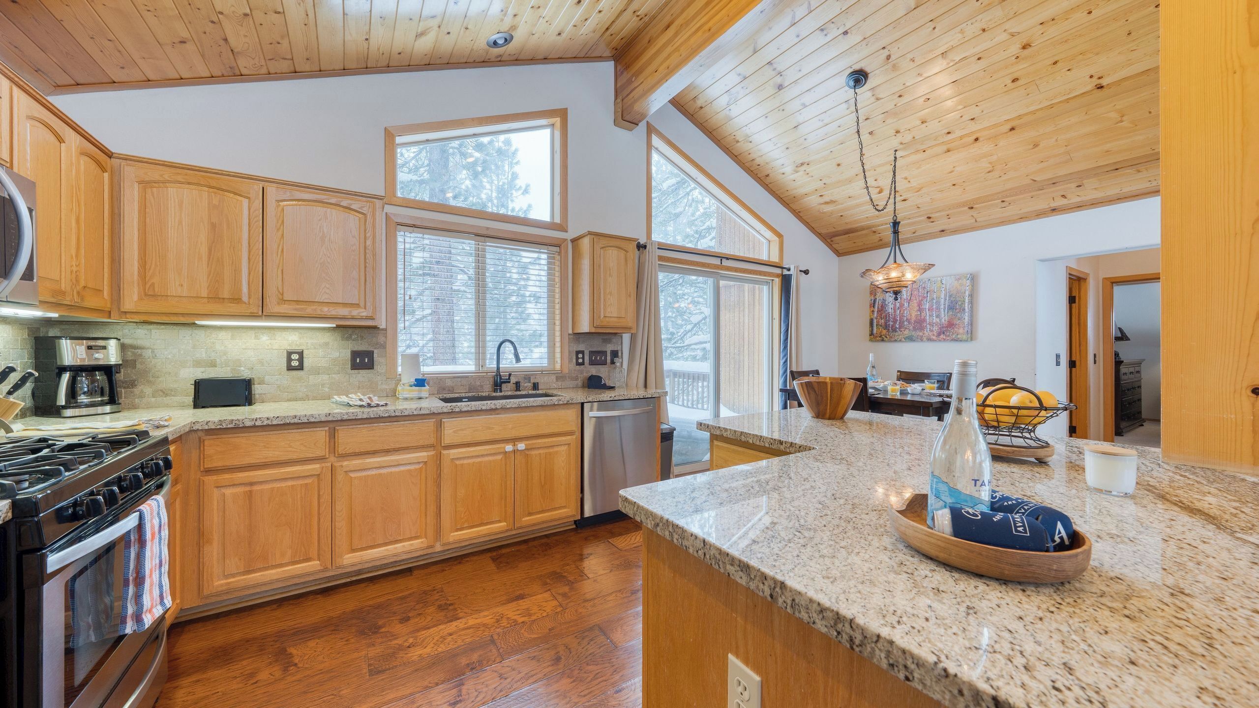 A kitchen with wooden cabinets, a granite countertop, a stove, and a dishwasher.