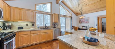 A kitchen with wooden cabinets, a granite countertop, a stove, and a dishwasher.