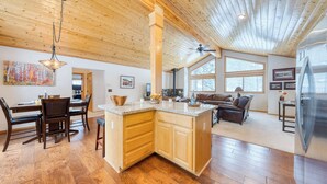 A spacious kitchen with wooden cabinets, a central island, and a dining area with a table and chairs. - Oslo Haus by Avantstay Cabin Retreat Near Northstar + Downtown Truckee (Truckee)