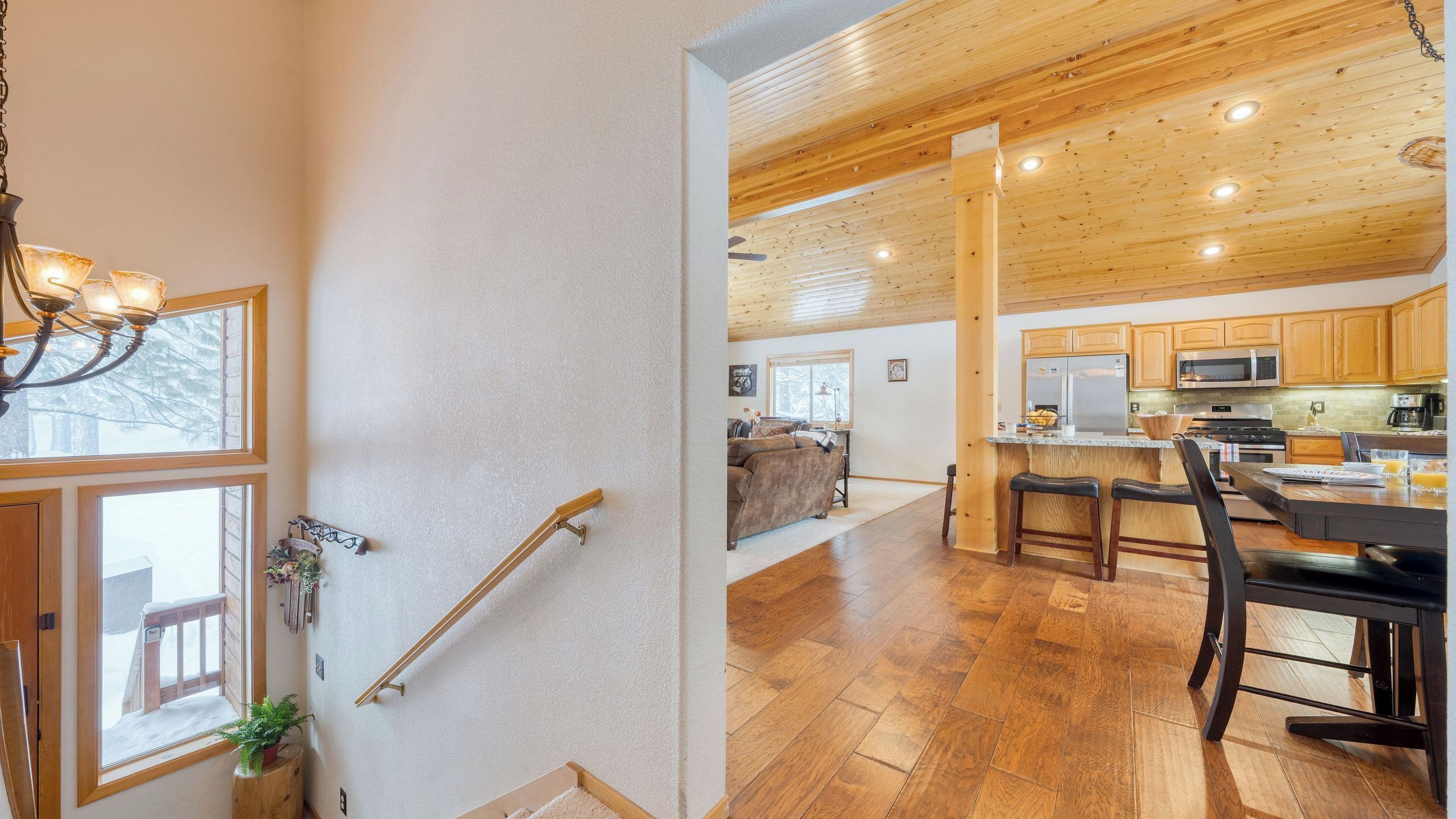 Eine moderne Küche mit Holzausstattung, ein Essbereich mit Tisch und Stühlen sowie eine Treppe mit Geländer.