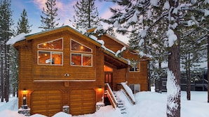 A wooden cabin with a garage, a staircase, and a snow-covered landscape. - Oslo Haus by Avantstay Cabin Retreat Near Northstar + Downtown Truckee (Truckee)