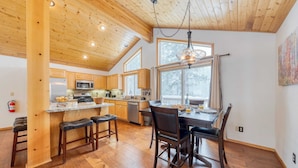 A spacious kitchen with wooden cabinets, a central island, and a dining area with a table and chairs. - Oslo Haus by Avantstay Cabin Retreat Near Northstar + Downtown Truckee (Truckee)