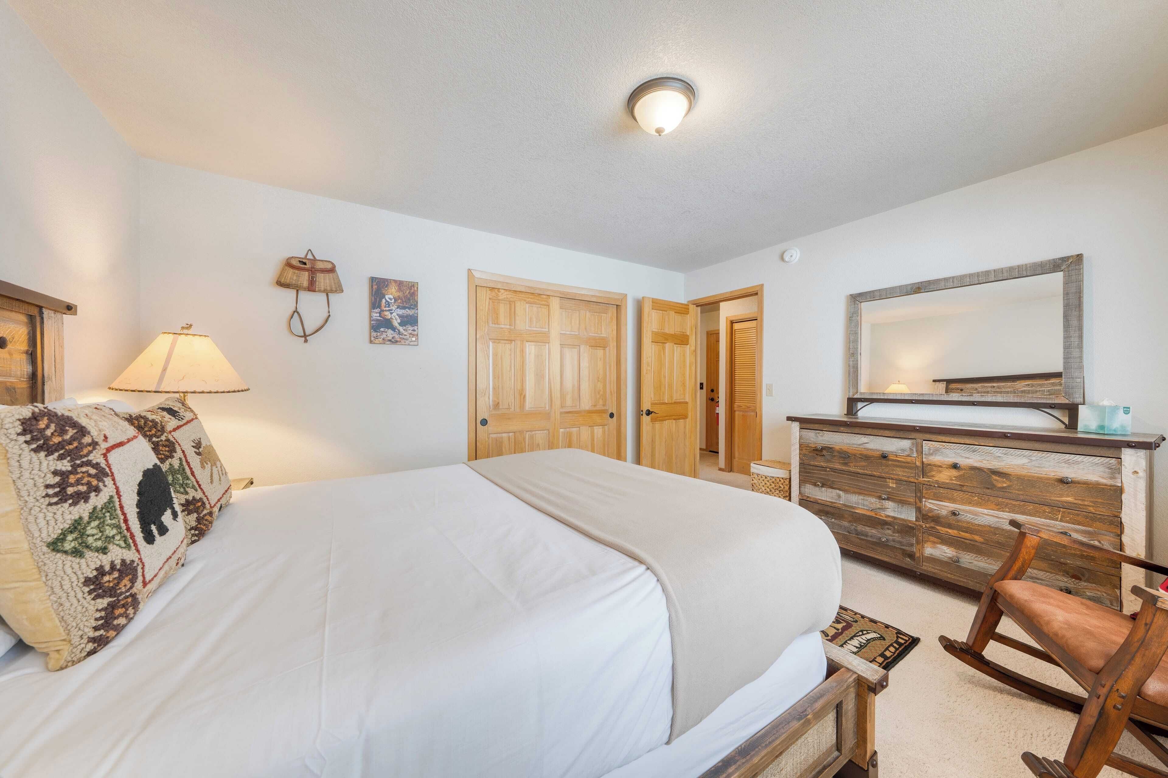 A bedroom with a bed, a dresser, a rocking chair, and a mirror.