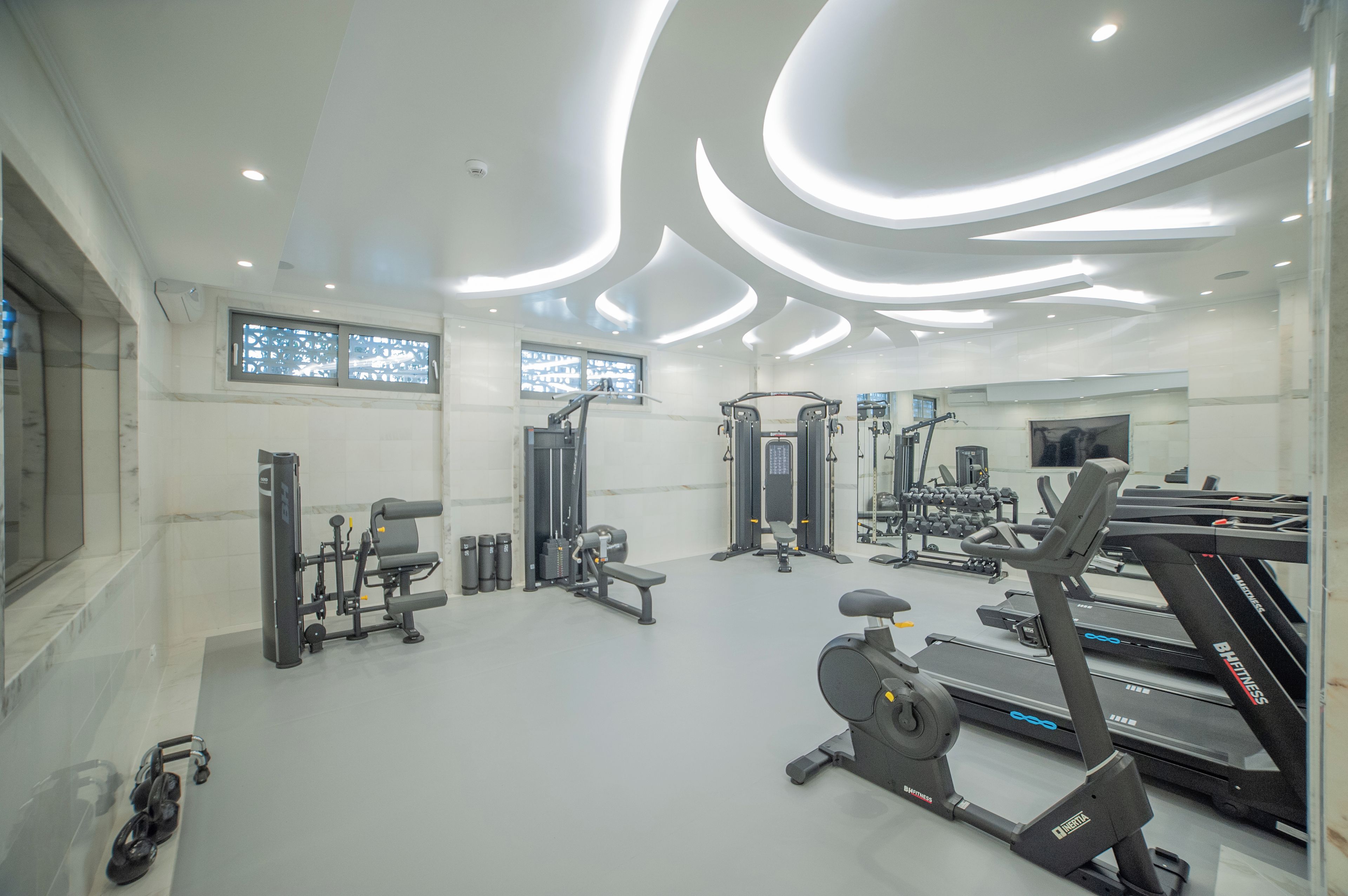 Un gimnasio moderno con diversos equipos de ejercicio, incluyendo cintas de correr y máquinas de pesas.
