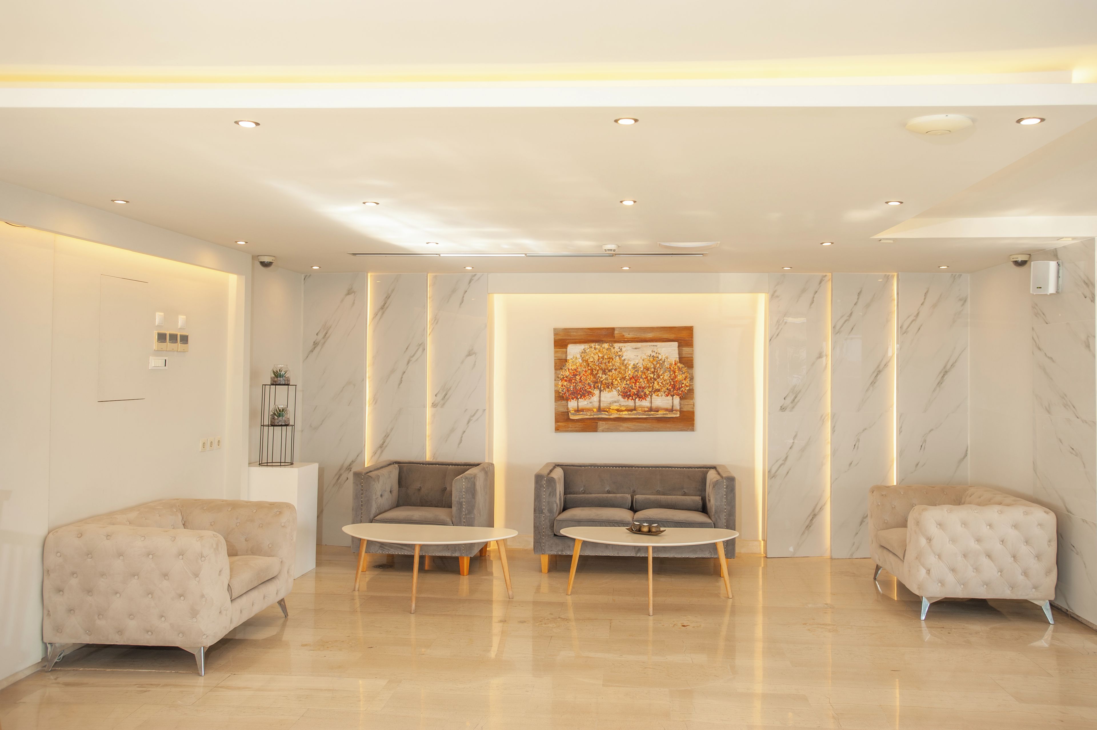Eine moderne Lobby mit Marmorwänden, zwei Sofas, einem Couchtisch und eingelassener Beleuchtung.
