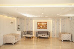 Eine moderne Lobby mit Marmorwänden, zwei Sofas, einem Couchtisch und eingelassener Beleuchtung.