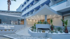 A hotel entrance with a modern design, featuring a staircase leading to the entrance, a sign for 'Rhodos Horizon Marina', and a landscaped area with cacti and palm plants. - Rhodos Horizon Marina (Rhodes)