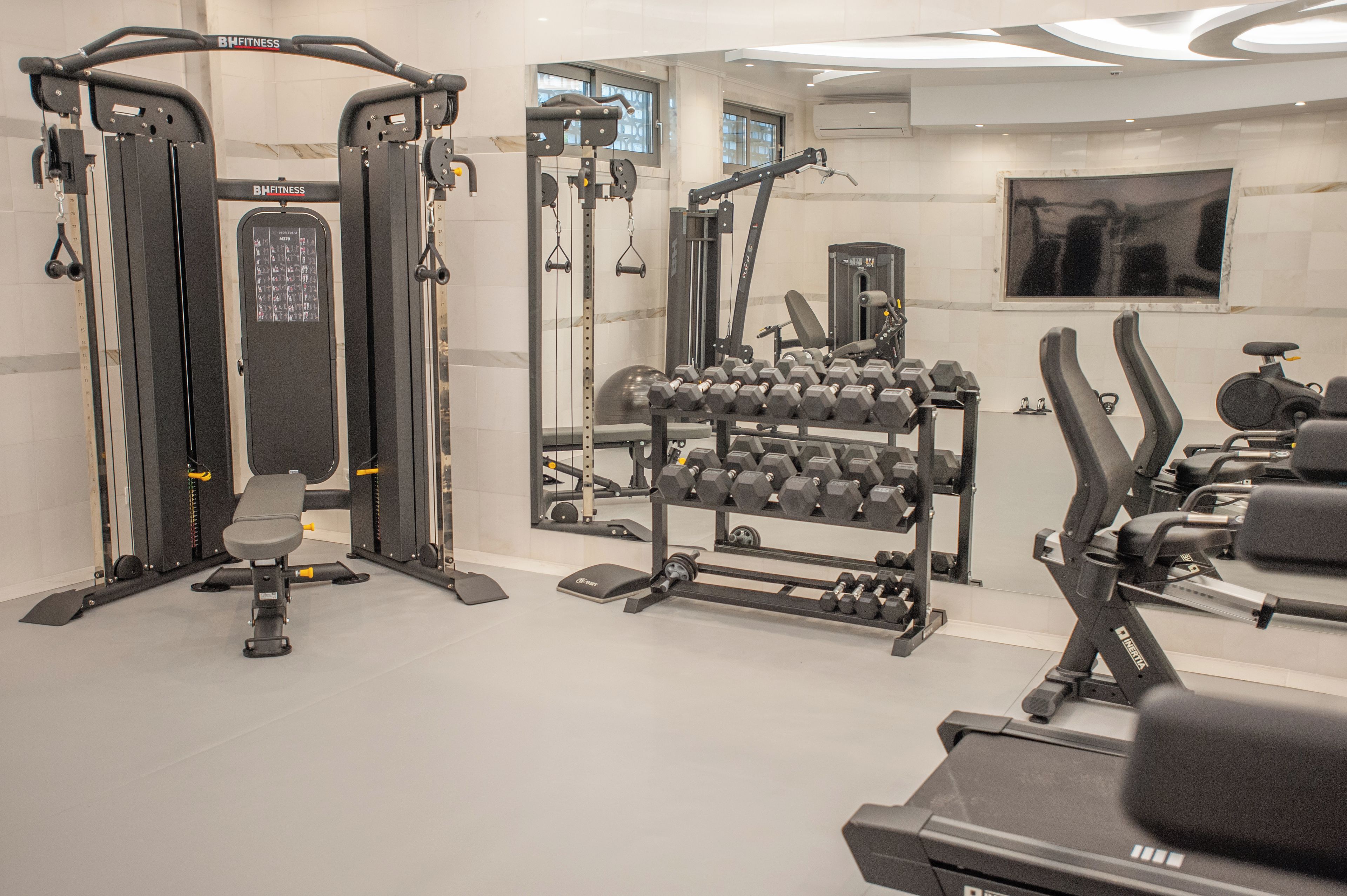 A gym with exercise equipment, a bench, and a mirror.