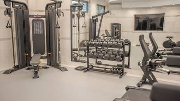 A gym with exercise equipment, a bench, and a mirror.