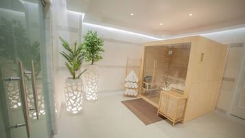 A modern hotel room with a glass door, a wooden cabinet, a plant, and a ladder.