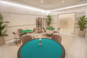 A modern indoor area with a round table, chairs, a bookshelf, and a sauna door. - Rhodos Horizon Marina (Rhodes)