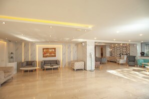 A spacious, modern living area with marble walls, multiple seating options, and a decorative wall panel. - Rhodos Horizon Marina (Rhodes)