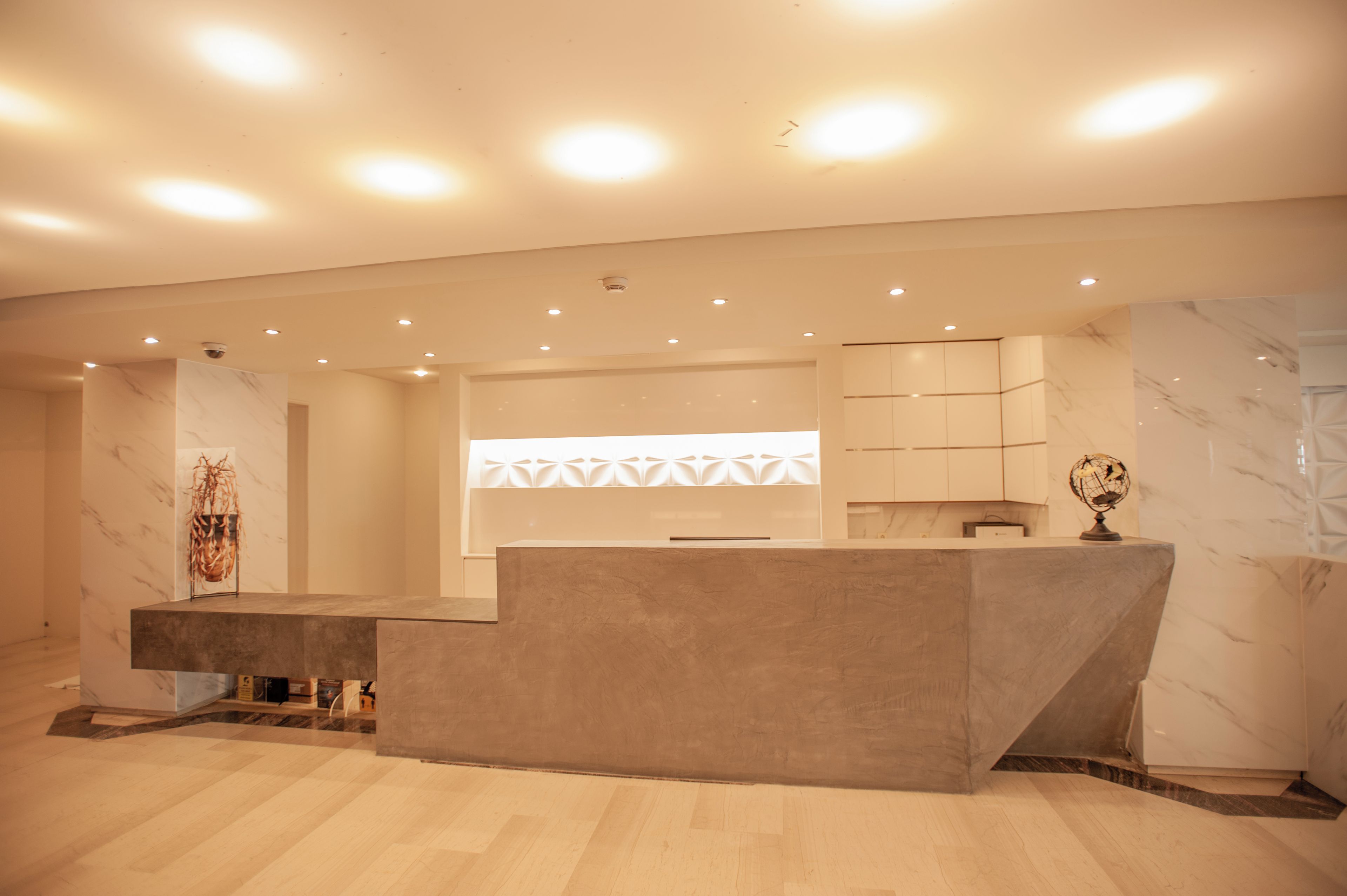 A modern reception area with a marble wall, a reception desk, and a globe as a decoration.
